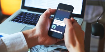 closeup of man holding phone with ai chatbot on it in front of laptop