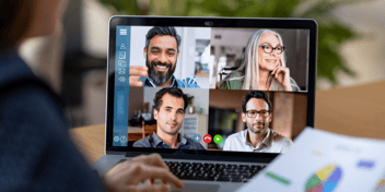 closeup of remote worker woman on a laptop with virtual meeting and four different coworkers on a virtual call