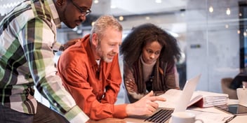 small business team gathered around laptop looking at screen in meeting